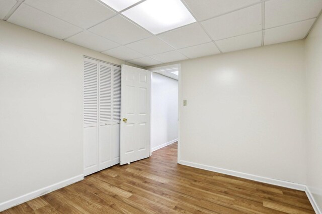 interior space featuring baseboards, light wood-style floors, and a paneled ceiling