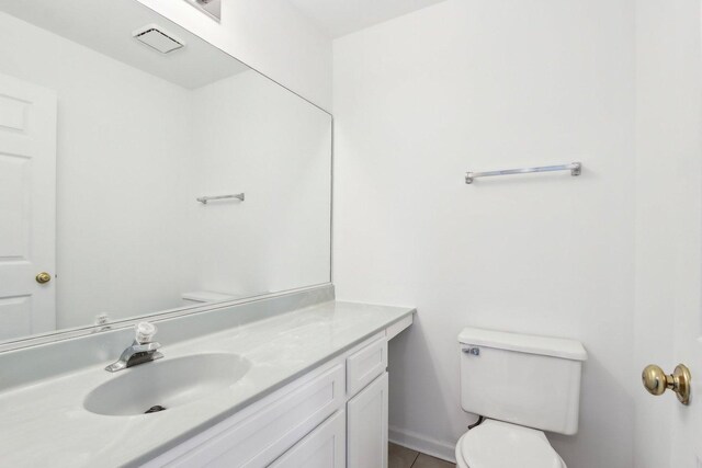 bathroom with vanity, baseboards, tile patterned flooring, and toilet