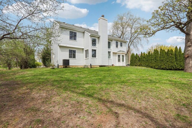 rear view of house featuring a lawn, central AC, and a chimney