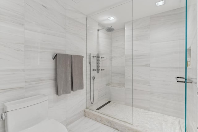 bathroom with tile walls, toilet, and a shower stall