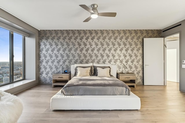 bedroom featuring wallpapered walls, wood finished floors, and ceiling fan