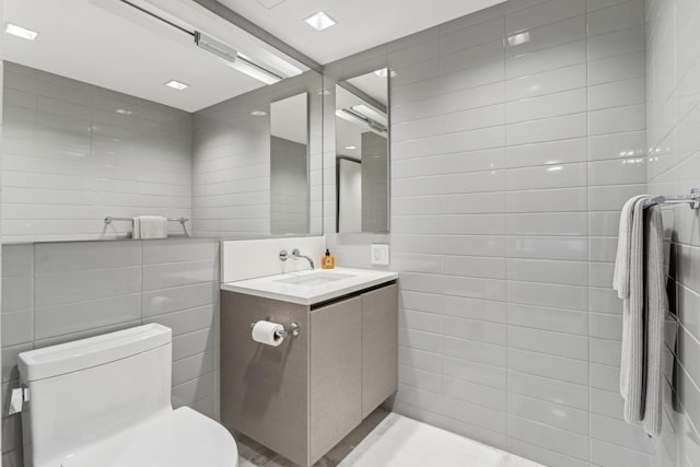 bathroom with tile walls, toilet, and vanity