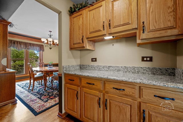 2527 Ryan Ct, Naperville, IL 60564 - kitchen with light wood finished floors, a chandelier, light stone countertops, and brown cabinetry