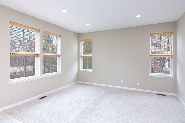 empty room featuring baseboards, recessed lighting, carpet, and visible vents
