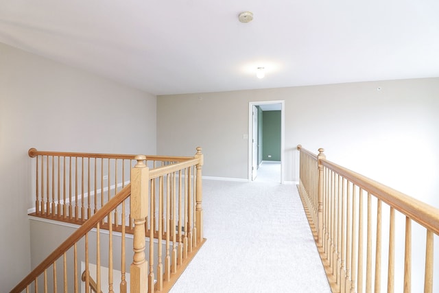hall with baseboards, carpet flooring, and an upstairs landing