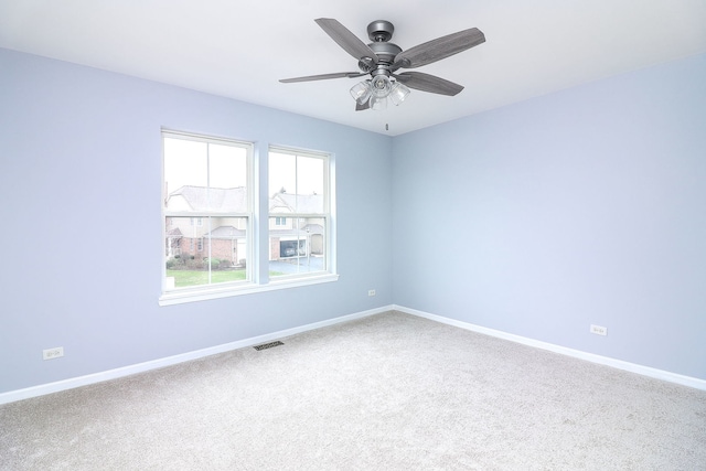 carpeted spare room with baseboards, ceiling fan, and visible vents