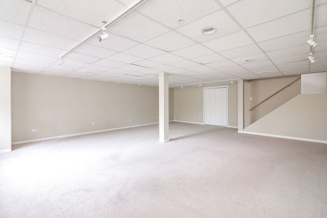 finished basement featuring baseboards, a drop ceiling, and carpet