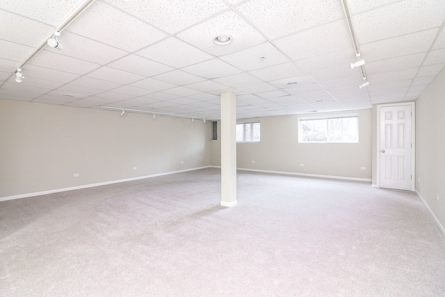 basement featuring baseboards, light carpet, and rail lighting