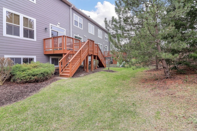 back of property with a deck, a yard, and stairway