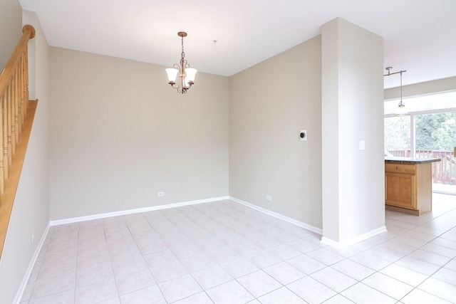 empty room featuring light tile patterned floors, baseboards, and a chandelier