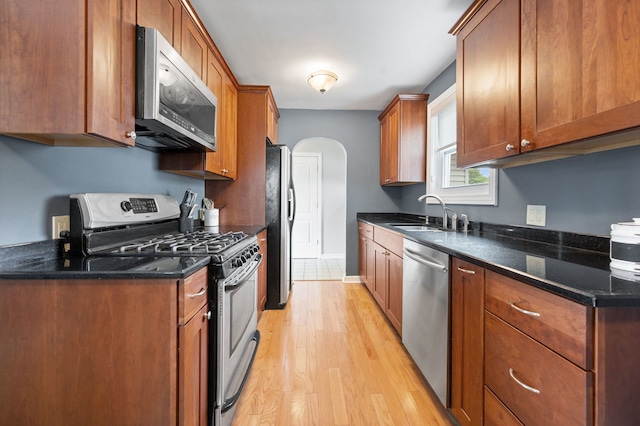 231 W Hickory Rd, Lombard, IL 60148 - kitchen featuring appliances with stainless steel finishes, light wood-type flooring, arched walkways, brown cabinets, and dark stone counters