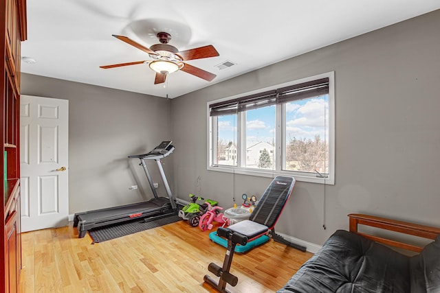 exercise area featuring baseboards, visible vents, a ceiling fan, and wood finished floors