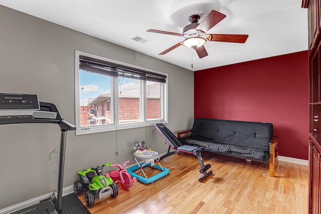 workout area with baseboards, visible vents, wood finished floors, and ceiling fan