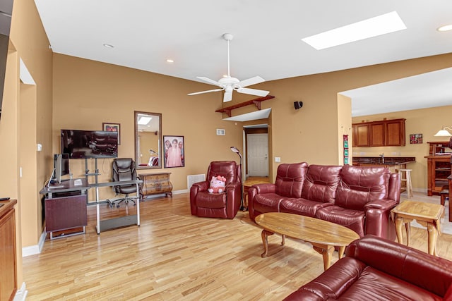 living area with recessed lighting, baseboards, a skylight, light wood finished floors, and a ceiling fan