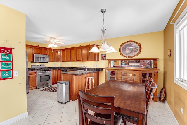 kitchen featuring light tile patterned floors, hanging light fixtures, a ceiling fan, a peninsula, and appliances with stainless steel finishes