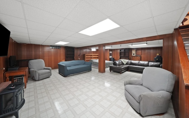 living room featuring wooden walls, tile patterned floors, and a paneled ceiling