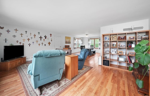 living area featuring a baseboard radiator, baseboard heating, and light wood-type flooring