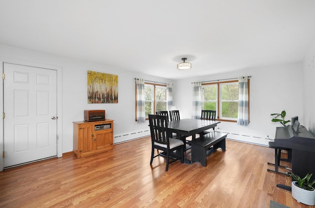 dining space with a baseboard heating unit and light wood-style floors