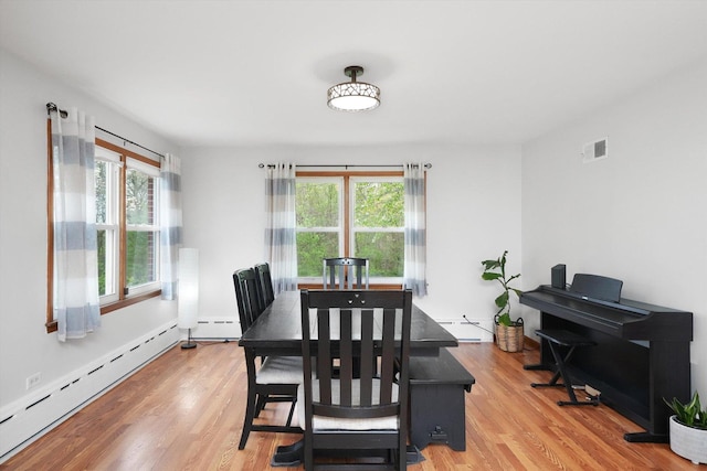 dining space with a baseboard heating unit, baseboard heating, and light wood-style floors