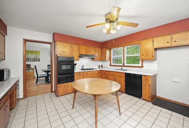 kitchen featuring a warming drawer, light countertops, under cabinet range hood, backsplash, and black appliances