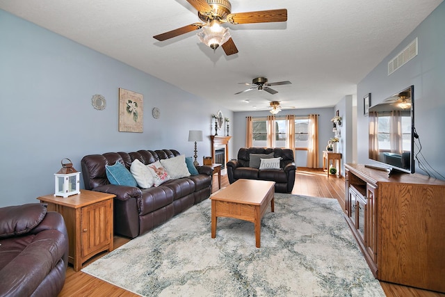 909 Revere St, Bourbonnais, IL 60914 - living room with wood finished floors, a textured ceiling, ceiling fan, and visible vents