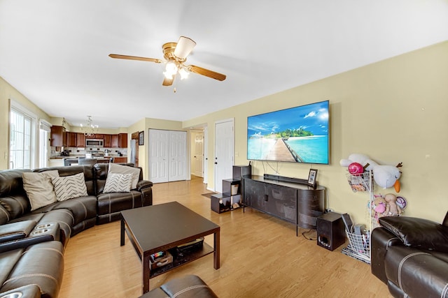 living area featuring ceiling fan with notable chandelier and light wood finished floors
