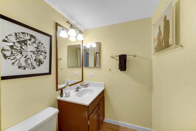 bathroom featuring toilet, vanity, and baseboards