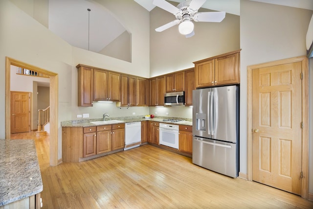 4517 S Seminole Dr, Glenview, IL 60026 - kitchen featuring appliances with stainless steel finishes, light stone countertops, a sink, high vaulted ceiling, and light wood-style floors