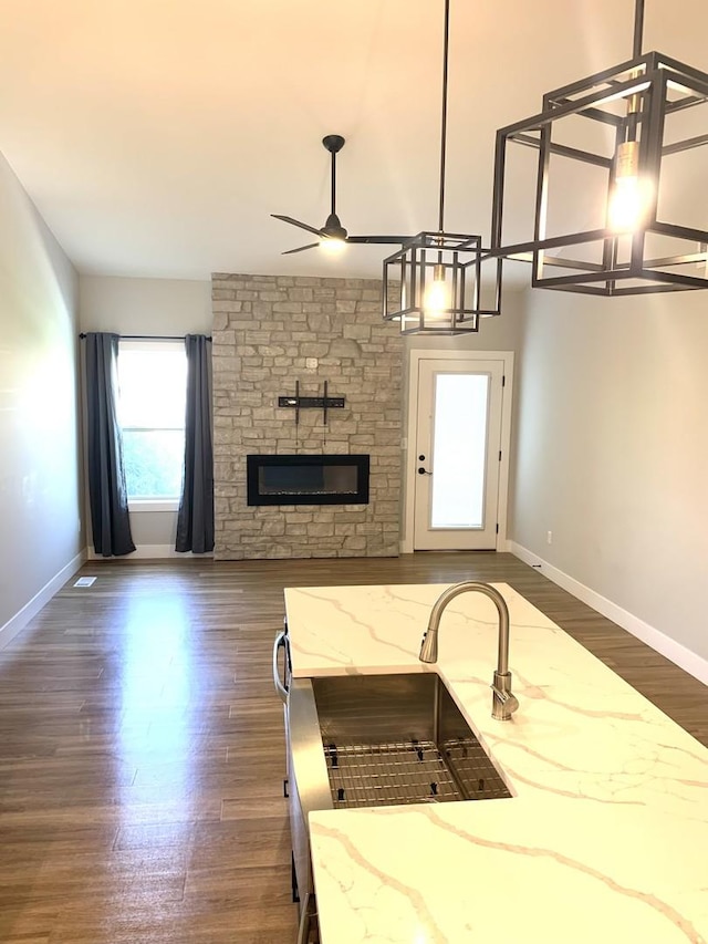 1805 Glenbridge Rd, Bloomington, IL 61704 - living room featuring a stone fireplace, a ceiling fan, baseboards, and dark wood-style flooring
