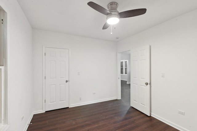 unfurnished room featuring baseboards, dark wood-style flooring, and a ceiling fan