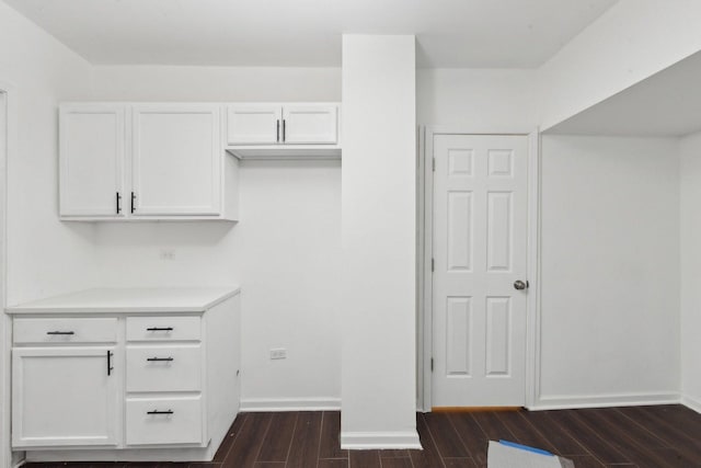 interior space featuring dark wood-type flooring, white cabinetry, baseboards, and light countertops