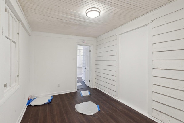 empty room featuring baseboards, wooden ceiling, and dark wood-style flooring