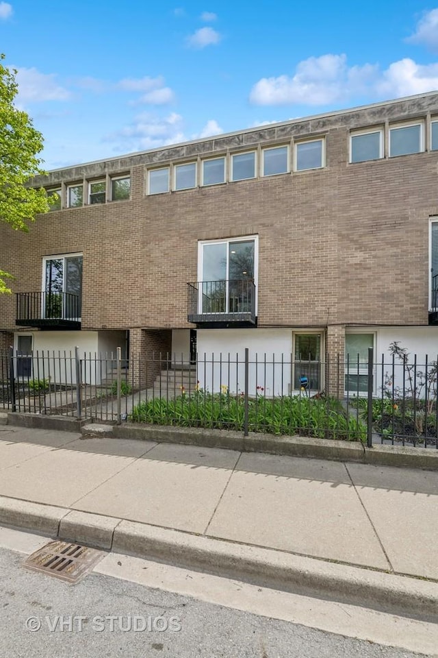 townhome / multi-family property featuring brick siding and a fenced front yard