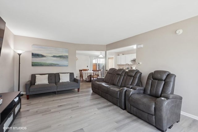 living area featuring baseboards and light wood-type flooring