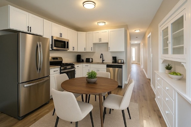 kitchen featuring a sink, white cabinets, stainless steel appliances, and light wood-style flooring