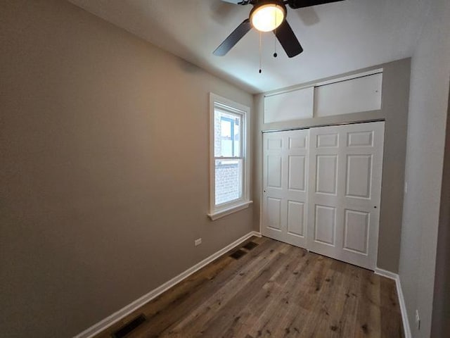 unfurnished bedroom with baseboards, a ceiling fan, wood finished floors, and a closet