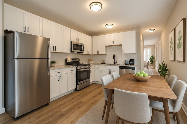kitchen with white cabinets, tasteful backsplash, and stainless steel appliances