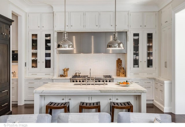 1853 N Burling St, Chicago, IL 60614 - kitchen with a kitchen bar, white cabinetry, a sink, glass insert cabinets, and backsplash