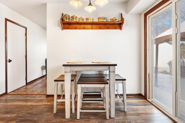 dining space with baseboards and wood finished floors