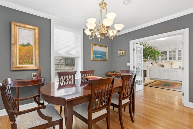 dining room featuring a chandelier, light wood finished floors, and crown molding