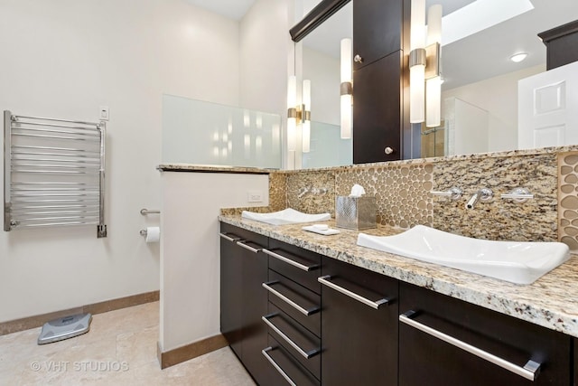 bathroom with tasteful backsplash, baseboards, double vanity, radiator heating unit, and a sink