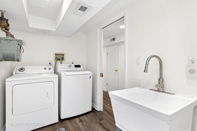 laundry area with laundry area, washing machine and clothes dryer, a sink, and visible vents