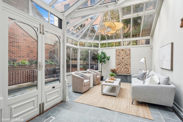 sunroom featuring outdoor lounge area, a wealth of natural light, baseboards, and stone tile flooring