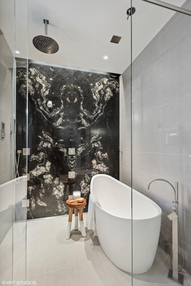 bathroom with tile patterned floors, a freestanding tub, tiled shower, and tile walls