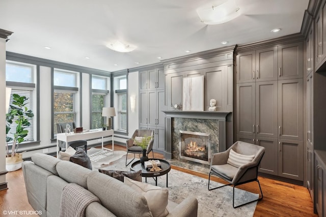 living room with a high end fireplace, light wood-style flooring, and recessed lighting