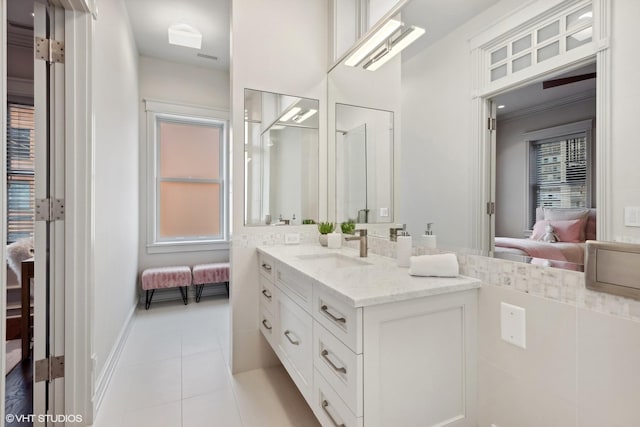 ensuite bathroom featuring tile patterned flooring, vanity, baseboards, and ensuite bath