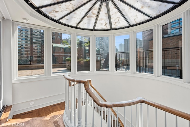 sunroom with baseboards, visible vents, wood finished floors, and a city view