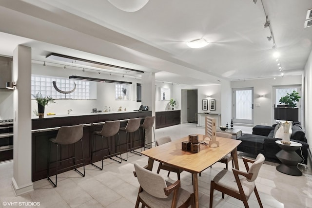 dining space with wet bar, light tile patterned floors, rail lighting, and visible vents
