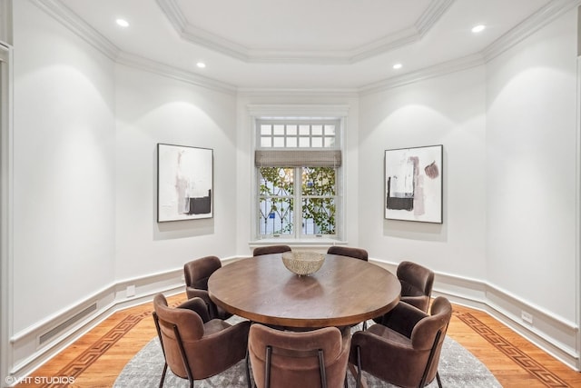 dining area featuring a tray ceiling, recessed lighting, crown molding, and light wood finished floors
