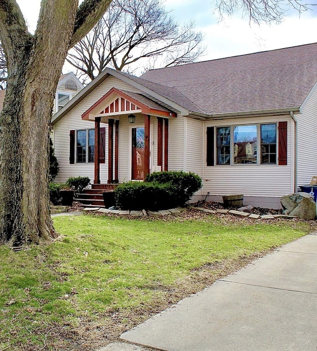 view of front facade with a front yard and a shingled roof